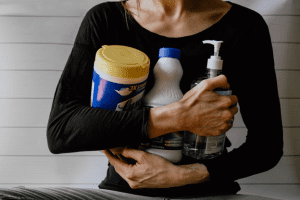 A person with hands full of cleaning supplies